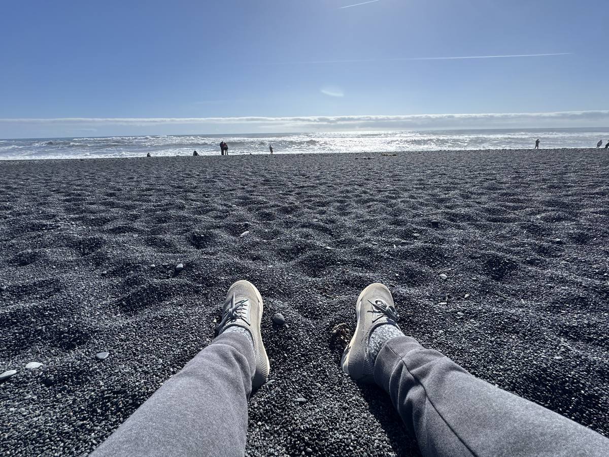 Wide black volcanic sand at Reynisfjara beach on Iceland's South Coast, the ocean breaking in the distance