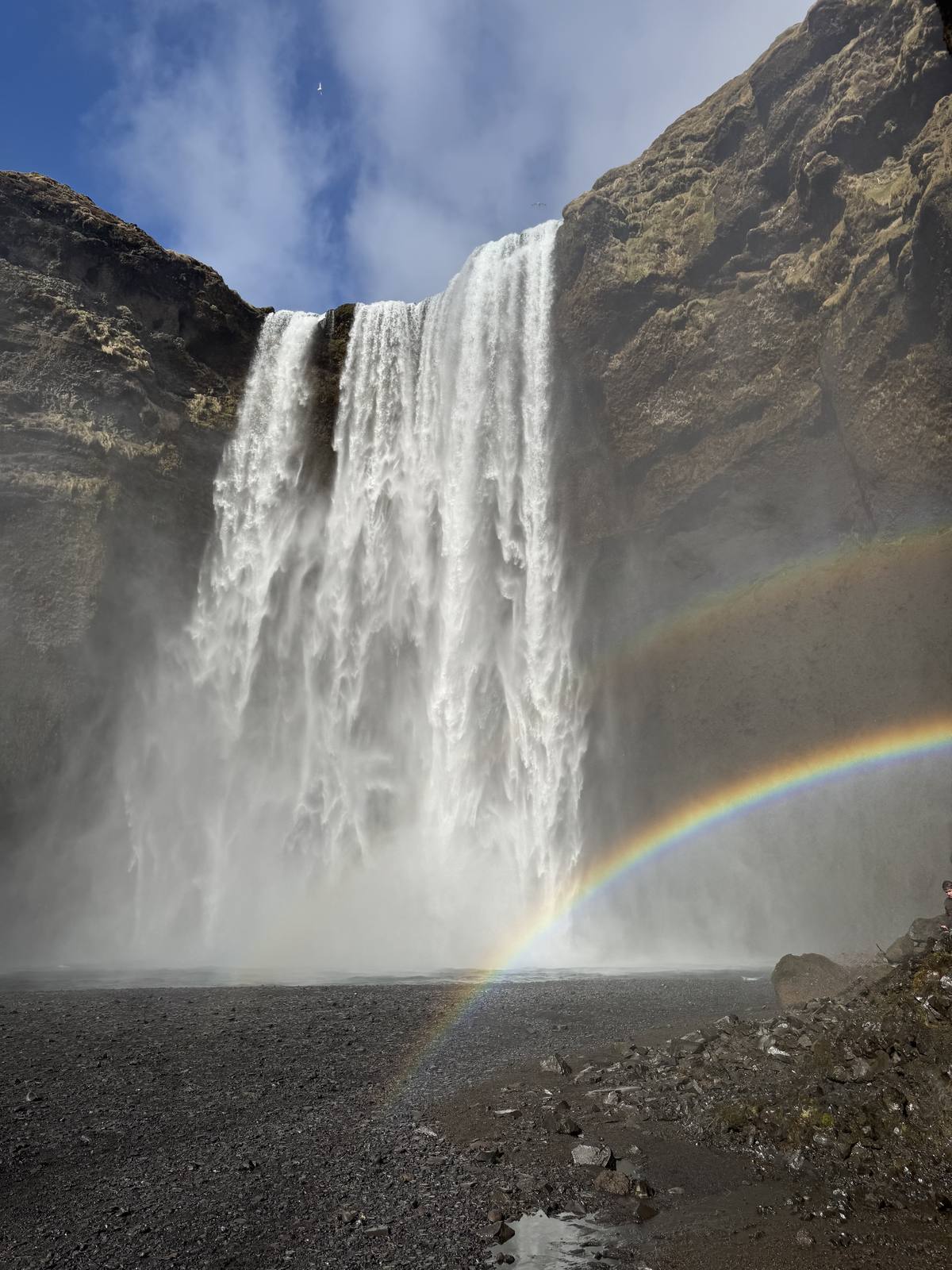 The wide curtain of Skogafoss waterfall with a rainbow in its spray on Iceland's South Coast