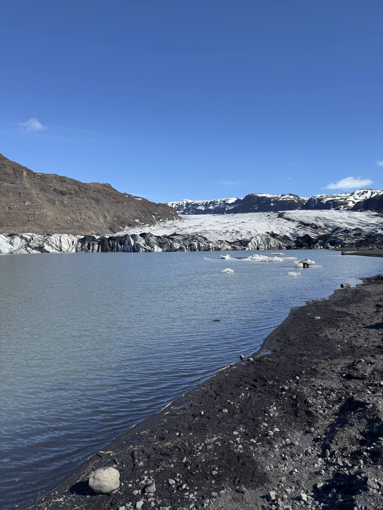The Solheimajokull glacier tongue meeting a grey meltwater lagoon, a South Coast tour photo stop