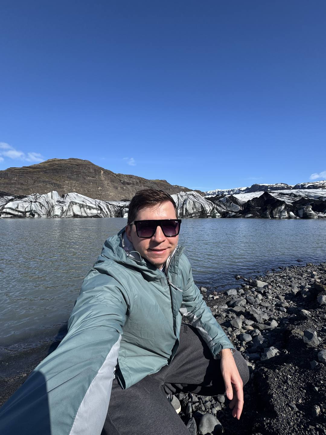 A traveler standing in front of the ash-streaked Sólheimajökull glacier tongue